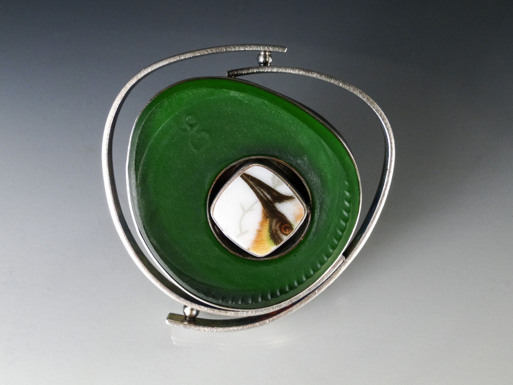 Amy Faust, Green Peekaboo Pin (2017). Repurposed glass and porcelain, recycled sterling silver. Dimensions: 2.5” x 2.5”. ©Amy Faust 2017. Courtesy of the artist.